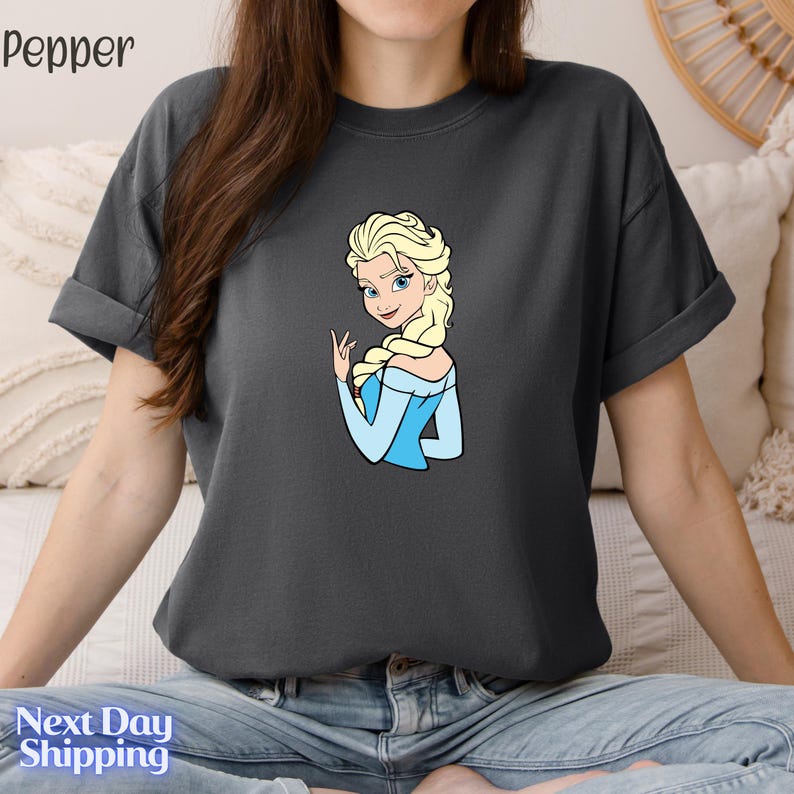 A woman wearing a gray t-shirt with a graphic of a blonde woman in blue dress.