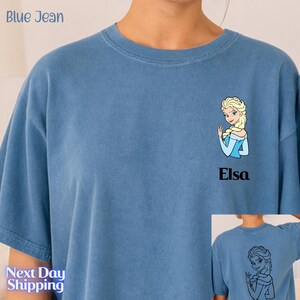 A person wearing a blue t-shirt with a cartoon image of a blonde woman and the name 'Elisa' printed on it.