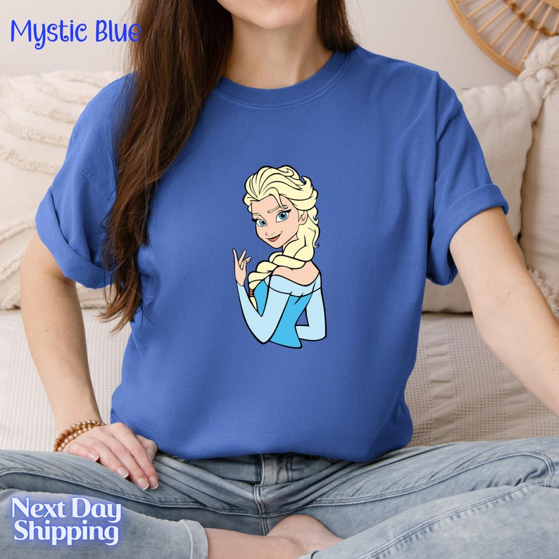 A woman wearing a blue t-shirt with a cartoon image of a blonde woman.