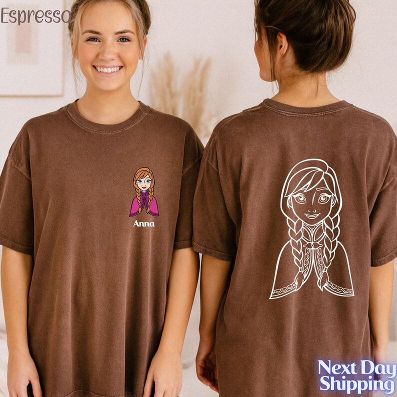 A smiling woman wearing a brown t-shirt with a cartoon character printed on the back.