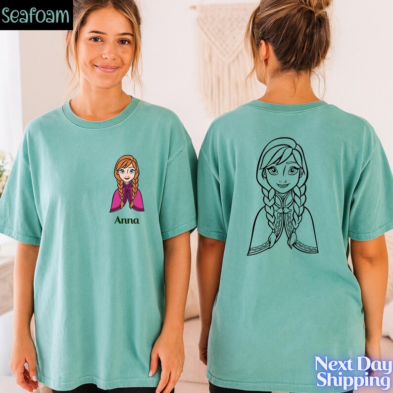 A woman wearing a teal t-shirt with a cartoon character printed on it, and the back of the t-shirt has a graphic of a woman with braids.