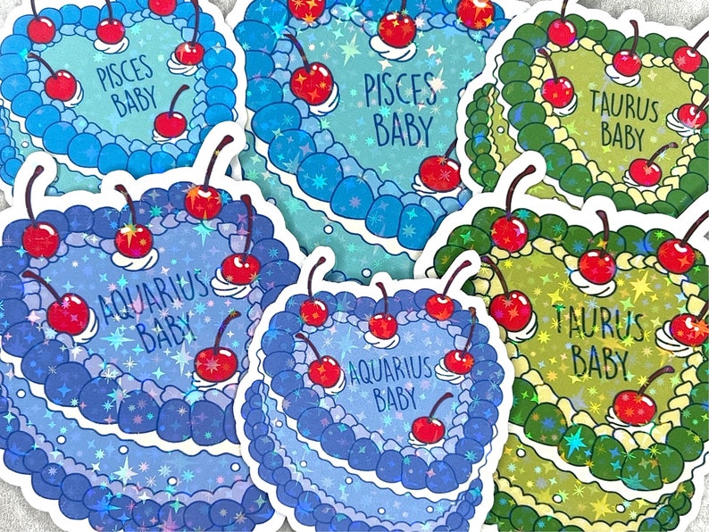 May include: Five holographic stickers featuring astrological signs with the text "Pisces Baby", "Taurus Baby", and "Aquarius Baby". Each sticker features a cake with cherries and a sparkly background.