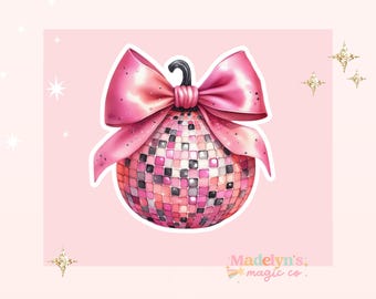 May include: A pink disco ball ornament with a large pink bow. The ornament is decorated with small squares of pink, black, and white.