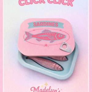 May include: A pink sardine can with the text "CLICK CLICK" at the top. The can is open, revealing two sardines inside. The can lid features a pink fish illustration and the word "SARDINES". The brand name "Madelyn's MAGIC CO." is at the bottom.