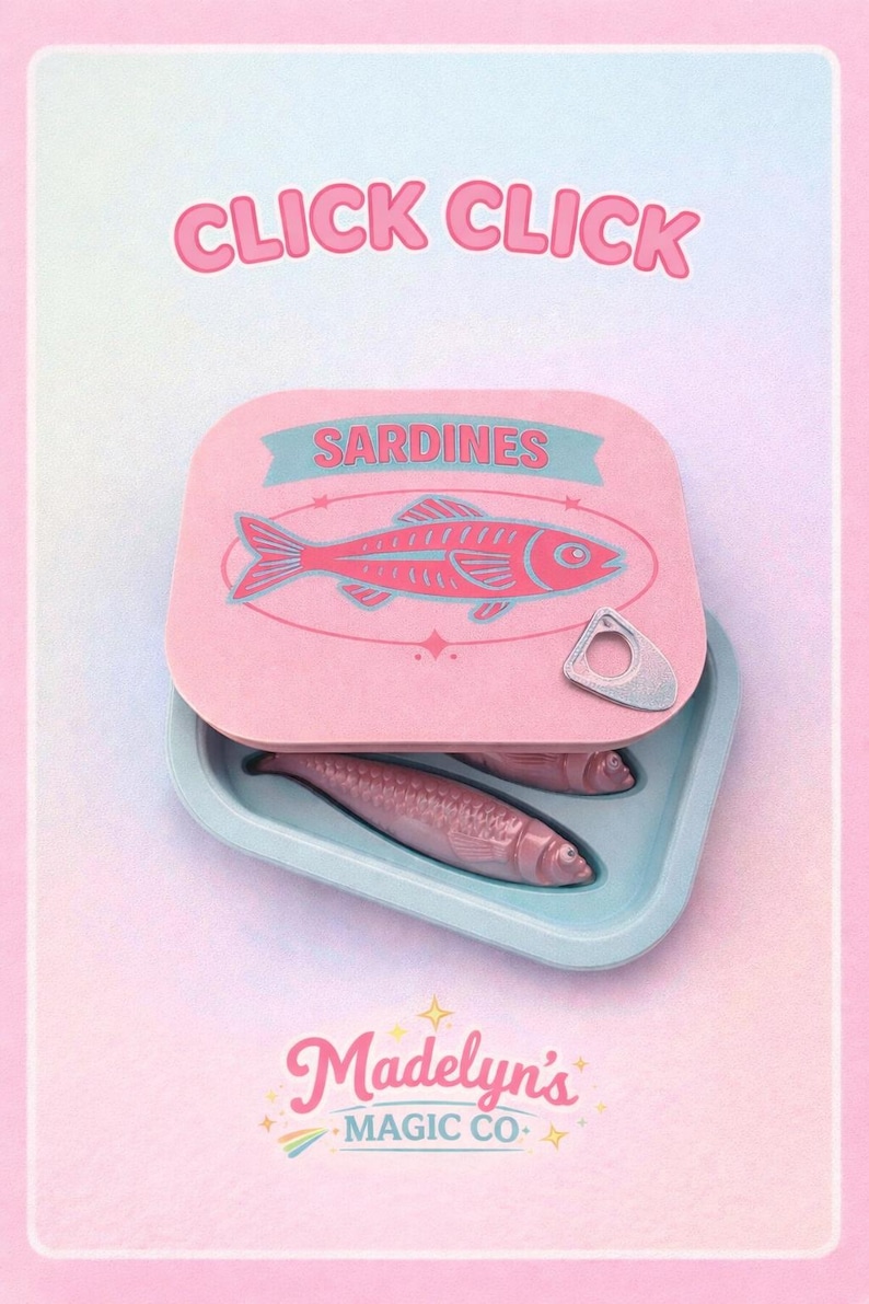 May include: A pink sardine can with the text "CLICK CLICK" at the top. The can is open, revealing two sardines inside. The can lid features a pink fish illustration and the word "SARDINES". The brand name "Madelyn's MAGIC CO." is at the bottom.