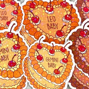 May include: Five colourful stickers featuring astrological signs with the text "Baby" and a heart shape. The stickers are decorated with cherries and stars. The signs are Gemini, Leo, Virgo.