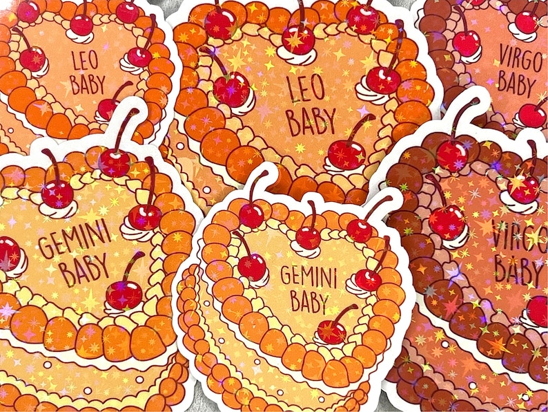 May include: Five colourful stickers featuring astrological signs with the text "Baby" and a heart shape. The stickers are decorated with cherries and stars. The signs are Gemini, Leo, Virgo.