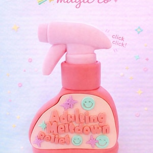 May include: A pink spray bottle with the text "Adulting Meltdown Relief" and the words "click click!" on the side. The bottle has a light pink trigger and a light pink base. The background is a pastel gradient with stars.