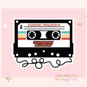 May include: A black cassette tape with the text "COSMIC REWIND" and "GUARDIANS OF THE GALAXY" on it. The tape has a white outline and is on a pink background.