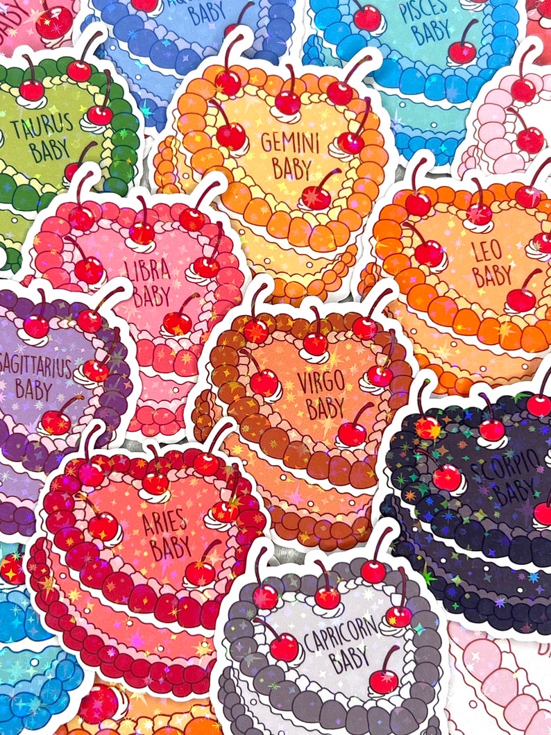 May include: Twelve holographic stickers featuring a cake with cherries and the zodiac signs. The stickers are in various colours, including pink, blue, green, orange, and brown.