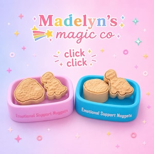 May include: Two rectangular containers in pastel pink and bright blue, each labeled Emotional Support Nuggets. Inside are tan, textured, nugget-shaped items resembling a dinosaur and a circle. Above, the text reads Madelyn's magic co and click click.