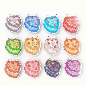 May include: Twelve heart-shaped cake pins with glitter and cherries. Each pin features a different zodiac sign with the text "Baby" underneath. The signs are Capricorn, Aquarius, Pisces, Aries, Taurus, Gemini, Cancer, Leo, Virgo, Libra, Scorpio, and Sagittarius.
