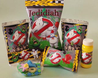 May include: A selection of Ghostbusters-themed party items. The image shows bags of sweets, Ring Pops, and a bubble bottle, all with the Ghostbusters logo and characters. The packaging has a caution tape design.