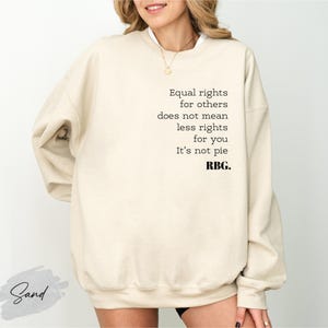 May include: A sand-colored sweatshirt with the text "Equal rights for others does not mean less rights for you. It's not pie. RBG." printed in black. The sweatshirt has long sleeves and a crew neck.