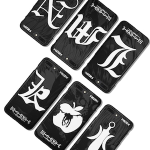 Op de afbeelding: Zwarte telefoonhoesjes met witte grafische ontwerpen. De hoesjes hebben verschillende gestileerde letters, een appel met een slang en andere symbolen. De tekst "DI--HNO-E" en "ROX" is zichtbaar. De hoesjes staan schuin op een witte ondergrond.