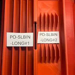 Könnte beinhalten: Zwei rote Kunststoff-Aufbewahrungsbehälter mit Trennwänden. Der Behälter links ist mit "PO-SLBIN -LONG#1" und der Behälter rechts mit "PO-SLBIN -LONG#2" beschriftet.