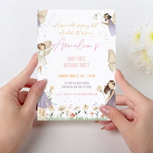 Może przedstawiać: Różowe i fioletowe zaproszenie na pierwszą urodzinową imprezę w stylu wróżek, z odrobiną magicznego pyłu i mnóstwem zabawy! Zaproszenie zawiera uroczą ilustrację wróżek i kwiatów. Tekst na zaproszeniu brzmi "Amelia's Fairy First Birthday Party" i zawiera datę, godzinę i miejsce imprezy.