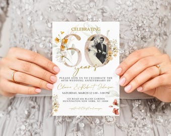 May include: A white invitation card with gold lettering announcing a 60th wedding anniversary celebration for Claire & Robert Johnson. The card features a photo of the couple and floral illustrations.