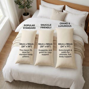 May include: Three cream-colored rectangular body pillows displayed on a white bed. The pillows are labeled with sizes: 50 inches by 150 inches (20 inches by 59 inches), 50 inches by 160 inches (20 inches by 63 inches), and 60 inches by 180 inches (24 inches by 71 inches).