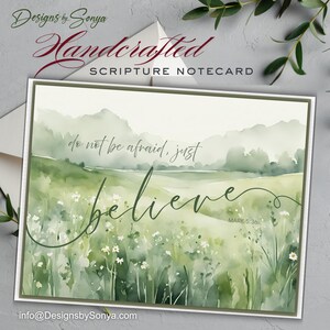 May include: A handcrafted scripture notecard with a watercolor landscape. The card features the words "do not be afraid, just believe" in elegant script, with "MARK 5:36" below. The design includes a green field and soft, muted colors.