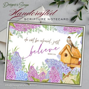 May include: Handcrafted scripture notecard with floral border in shades of purple, blue, and white. The card features the text "do not be afraid, just believe" and a small bird perched on a wooden birdhouse. The card is from Designs by Sonya.
