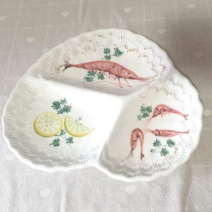 Puede incluir: Plato blanco para servir con tres secciones y borde festoneado. El plato está decorado con ilustraciones de camarones rosas, rodajas de limón y ramitas verdes. Ideal para servir aperitivos o porciones pequeñas.