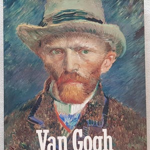 May include: A book cover displaying a portrait of Vincent van Gogh, with the artist's name in large white letters. The portrait shows Van Gogh wearing a hat, with a red beard and a serious expression. The background is a blend of blues and greens.