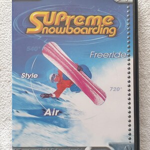 Puede incluir: Caja de CD-ROM para PC de "Supreme Snowboarding" con un snowboarder en acción. La portada es azul, con el título del juego en dorado y una tabla de snowboard rosa. Incluye texto como "Freeride", "Style" y "Air".