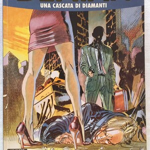May include: A comic book titled DEMIAN UNA CASCATA DI DIAMANTI featuring a cover illustration of a person in a skirt and high heels standing over a prone figure, while a person in a suit holds a gun and a briefcase in the background.