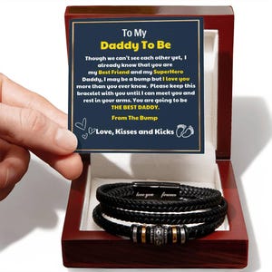 May include: A black braided leather bracelet with a magnetic clasp, presented in a wooden box. The bracelet has the words "love you forever" engraved on the clasp. A card inside the box reads "To My Daddy To Be".