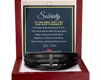 May include: A red wooden box containing a black leather bracelet with a cross charm. The box includes a card with the message: "Sobriety is the best gift you can give yourself!"  "Your best days are ahead of you. The movie starts when the guy gets sober, and puts his life back together. It doesn't end there. Stay strong, I always believe in you. Love, Elena"