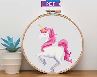 May include: A cross-stitch pattern of a white unicorn with a pink mane and tail, framed in a wooden hoop. The unicorn is standing on its hind legs with its head turned to the side.
