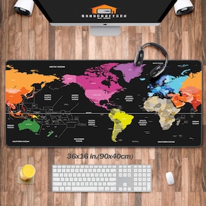 Può includere: Tappetino da scrivania nero con un design colorato della mappa del mondo. Il tappetino misura 90x40cm e presenta i continenti in vari colori. Il testo "KOHDERAFISCO" è visibile sul monitor. Sono presenti anche una tastiera, un mouse e delle cuffie.