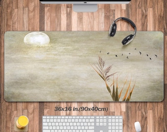May include: A rectangular desk mat with a nature-inspired design. The mat features a full moon, reeds, and flying birds against a muted background. The mat measures 36 x 16 inches.