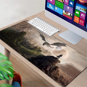K&ouml;nnte beinhalten: Eine Fantasy-Mausmatte mit einem dunkelgrauen Drachen, der &uuml;ber eine felsige Landschaft mit einem Mond im Hintergrund fliegt. Die Mausmatte liegt auf einem Holztisch mit einer Tastatur und einem Computermonitor.