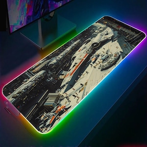 Pode incluir: Um grande tapete de rato retangular com uma borda colorida, semelhante a um arco-íris. O tapete de rato apresenta uma imagem detalhada de uma nave espacial num ambiente de cidade futurista.