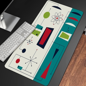 May include: A white and teal desk mat with a mid-century modern design. The design features red, green, and black geometric shapes, including circles, stars, and rectangles.