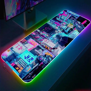 Peut inclure: Un tapis de souris de jeu noir et bleu avec une bordure arc-en-ciel néon. Le tapis de souris présente une scène de ville avec des enseignes au néon et une personne tenant un parapluie.