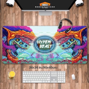 May include: A large, rectangular mouse pad with a colorful, fantasy-themed design. The pad features a central circular logo with the text "HYPER BEAST" and measures 36 x 16 inches (90 x 40cm). The design includes vibrant blues, purples, and oranges.