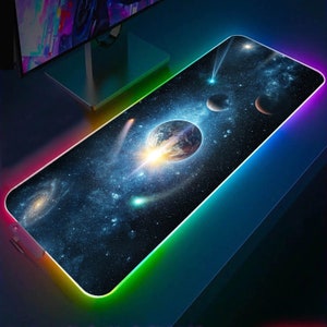 May include: A black and blue gaming mouse mat with a colourful LED light border. The mouse mat features a space-themed design with a planet, stars, and a comet.