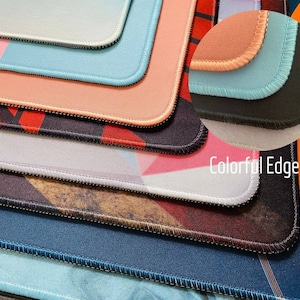 May include: Close-up of several colorful mouse pads with stitched edges. The pads feature various designs, including geometric patterns and solid colors. The text "Colorful Edge" is visible.