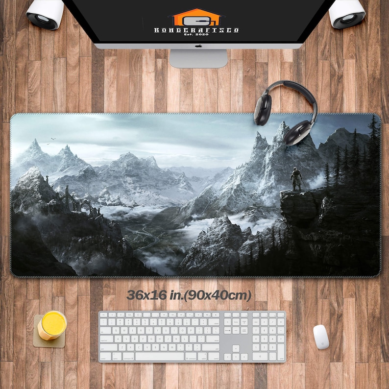 K&ouml;nnte beinhalten: Eine gro&szlig;e, schwarz-wei&szlig;e Gaming-Mausmatte mit einer schneebedeckten Berglandschaft und einer einsamen Figur, die auf einer Klippe steht. Die Mausmatte misst 90x40 cm (36x16 Zoll).