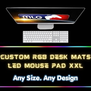 May include: A black desk setup featuring a computer monitor displaying the MLG logo, a white keyboard, and a large, rectangular RGB LED mouse pad. The mouse pad has the text "CUSTOM RGB DESK MATS LED MOUSE PAD XXL" and "Any Size. Any Design."
