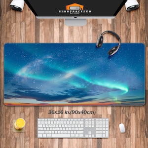 Puede incluir: Un gran tapete de ratón rectangular con un borde cosido, que muestra un diseño de aurora boreal azul y verde. El tapete de ratón mide 36x16 pulgadas (90x40 cm).