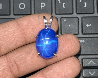 May include: A blue star sapphire pendant with a silver setting. The sapphire has a star-like pattern in the center.