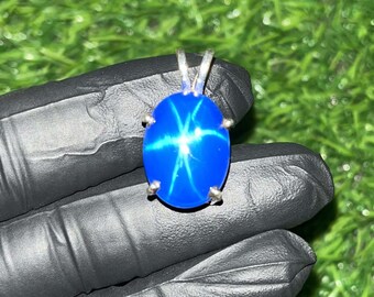 May include: A silver pendant featuring a blue star sapphire gemstone with a starburst pattern.