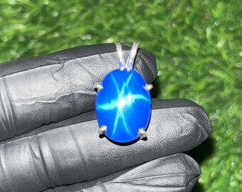 May include: A silver pendant featuring a blue star sapphire gemstone with a starburst pattern.