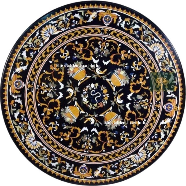 May include: A round black marble table top with intricate gold and white floral designs. The table top is inlaid with various colored stones and features the text "The Golden Leaf India".