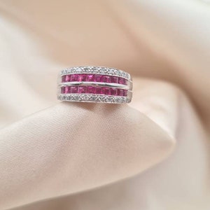 May include: A silver ring with two rows of pink square-shaped gemstones and a row of smaller white gemstones.