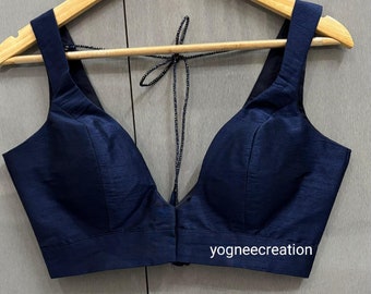 Peut inclure: Un chemisier bleu marine sans manches avec un décolleté en V profond et une fermeture à nouer dans le dos. Le chemisier a un corsage ajusté et une ourlet droit. Le texte "yogneecreation" est visible dans le coin inférieur droit du chemisier.